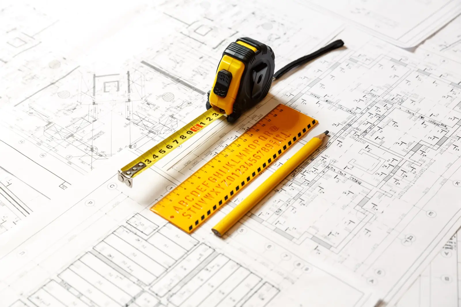 Tape measure, lettering stencil and pencil on construction plans