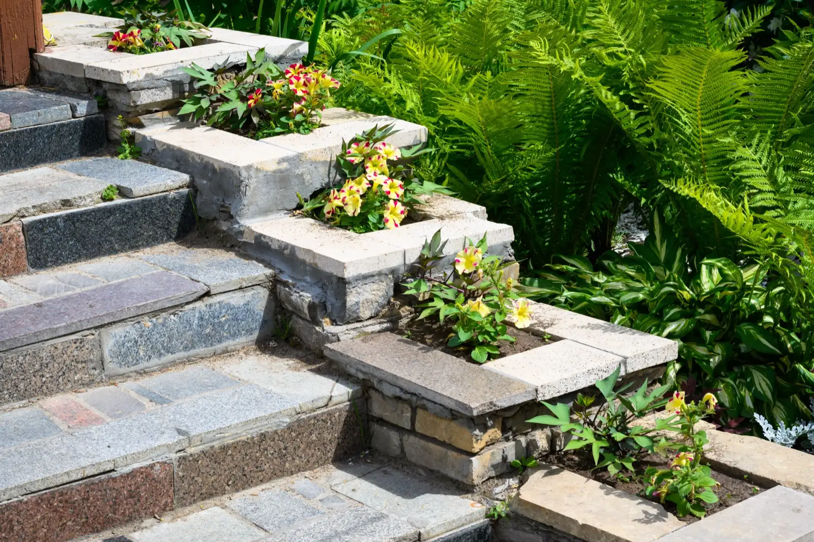 Stone garden steps beside stepped retaining wall planters with flat caps